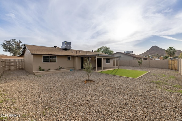 rear view of house featuring a fenced backyard, central AC unit, a mountain view, and a patio