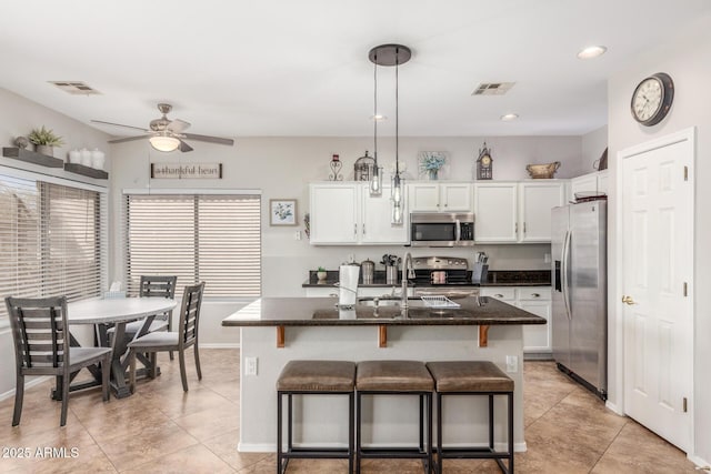 kitchen with a kitchen bar, visible vents, a center island with sink, white cabinetry, and appliances with stainless steel finishes