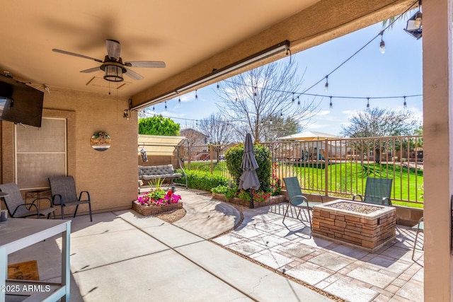 view of patio featuring a fire pit, fence, ceiling fan, and a playground