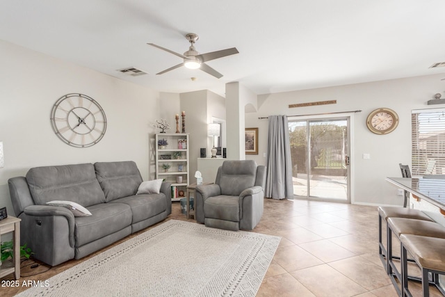 living room with light tile patterned floors, visible vents, baseboards, and a ceiling fan