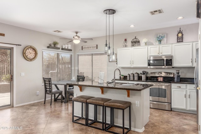 kitchen with visible vents, a kitchen bar, appliances with stainless steel finishes, white cabinetry, and a sink