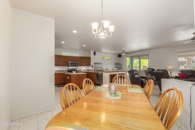 tiled dining area featuring ceiling fan with notable chandelier