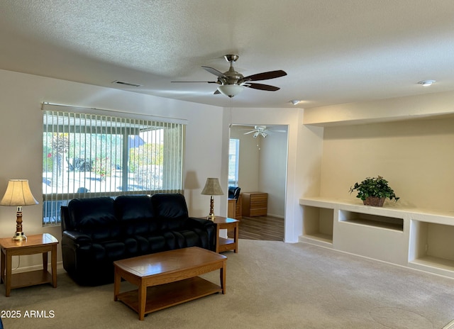 living room with a textured ceiling, ceiling fan, built in features, and light carpet