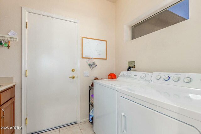 laundry room featuring cabinets, light tile patterned floors, and washing machine and clothes dryer