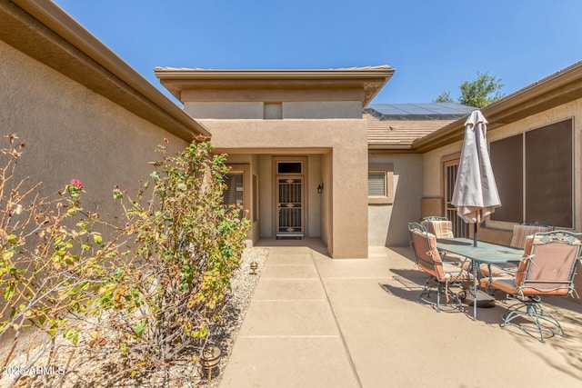 property entrance with solar panels and a patio