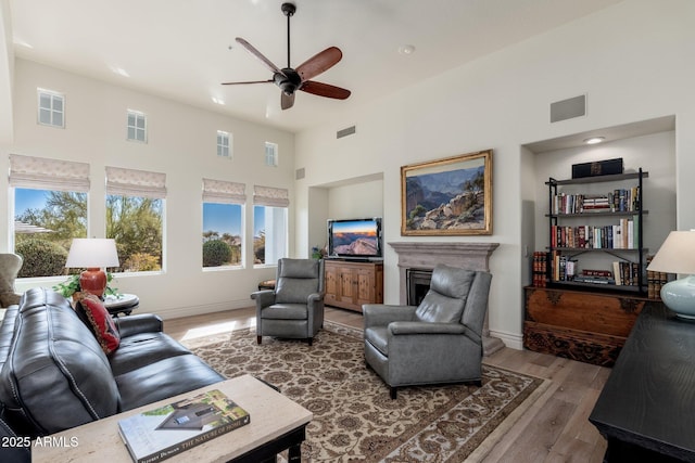 living area with a high ceiling, a fireplace, wood finished floors, and visible vents