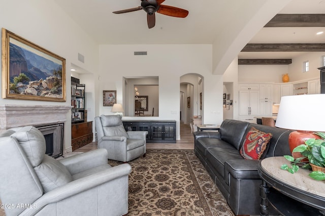 living room with arched walkways, beam ceiling, a fireplace, visible vents, and a ceiling fan