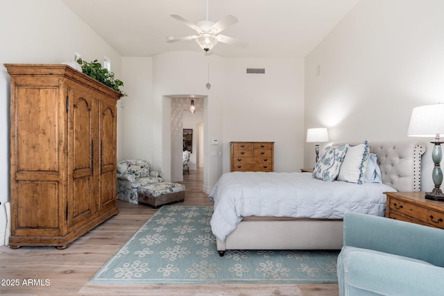 bedroom featuring light wood-style floors, visible vents, and a ceiling fan