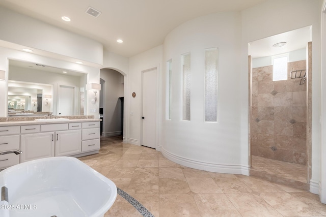 full bathroom featuring a freestanding bath, a walk in shower, visible vents, and baseboards