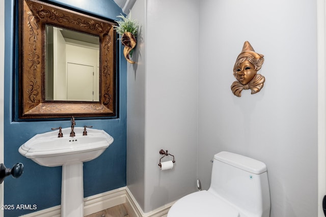 bathroom with baseboards, a sink, and toilet