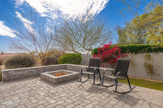 view of patio featuring an outdoor fire pit and fence