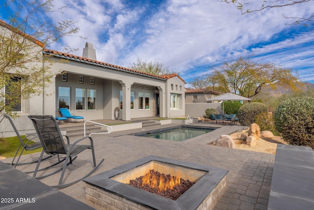 back of property with a patio area, a tile roof, a chimney, and stucco siding