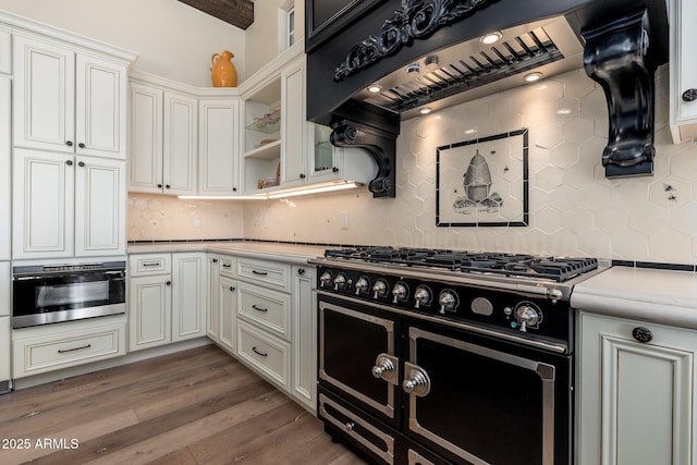 kitchen featuring range with two ovens, light countertops, wall oven, ventilation hood, and wood finished floors