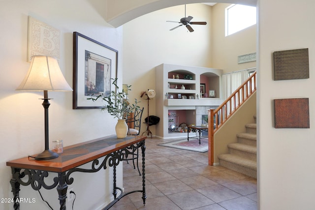 entryway with a high ceiling, ceiling fan, and light tile patterned flooring