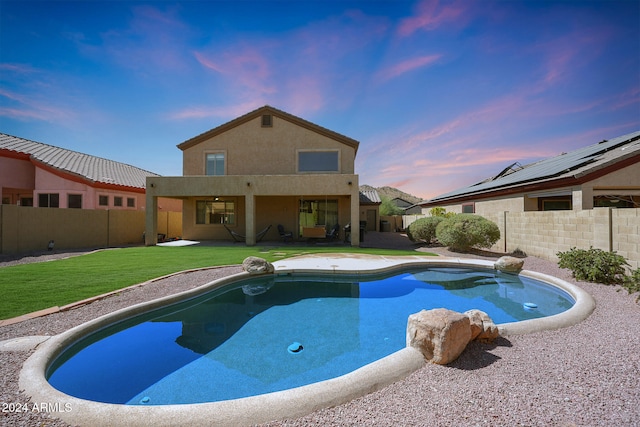 pool at dusk with a patio and a lawn