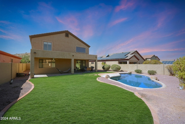 pool at dusk with a patio and a lawn