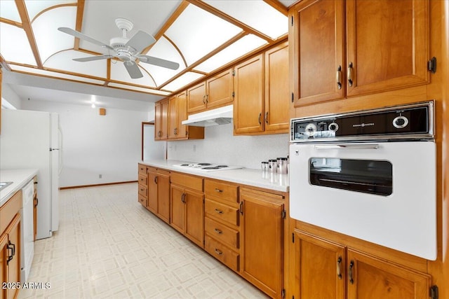 kitchen with white appliances, brown cabinetry, light floors, light countertops, and under cabinet range hood