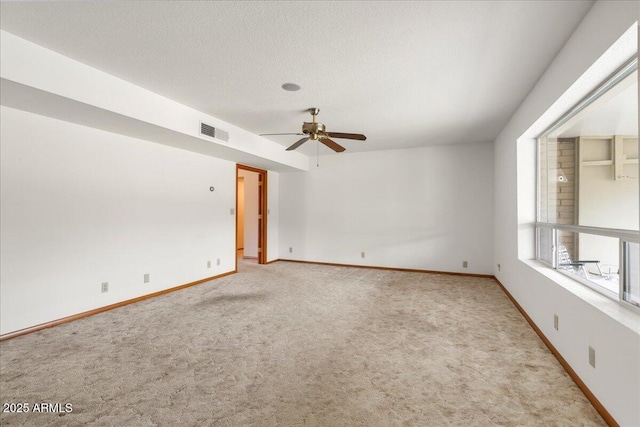 carpeted empty room with a textured ceiling, ceiling fan, visible vents, and baseboards