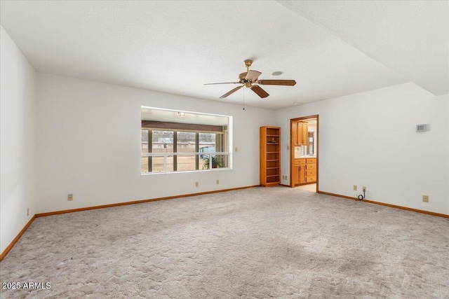 empty room with baseboards, a ceiling fan, and light colored carpet