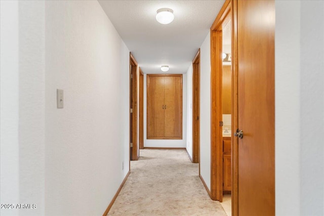 hallway with light colored carpet and baseboards