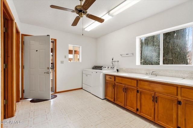 laundry room with laundry area, washer and clothes dryer, a ceiling fan, light floors, and a sink