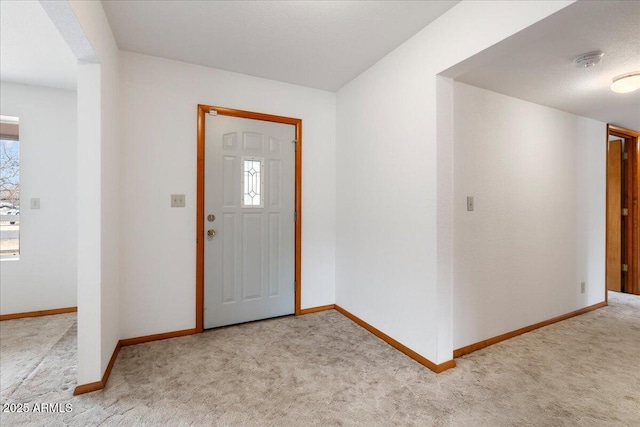 foyer featuring carpet flooring and baseboards