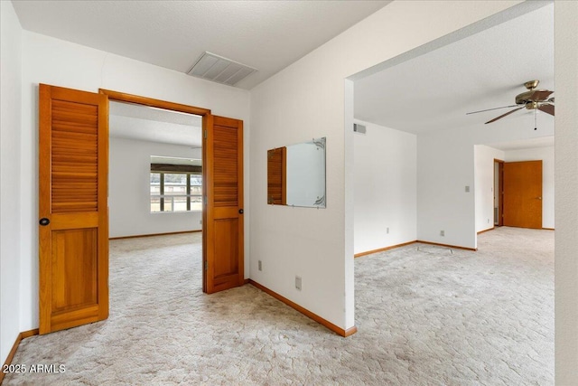 spare room with light colored carpet, visible vents, and ceiling fan