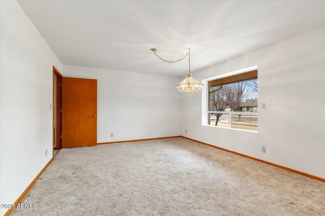 spare room featuring a notable chandelier, baseboards, and carpet flooring