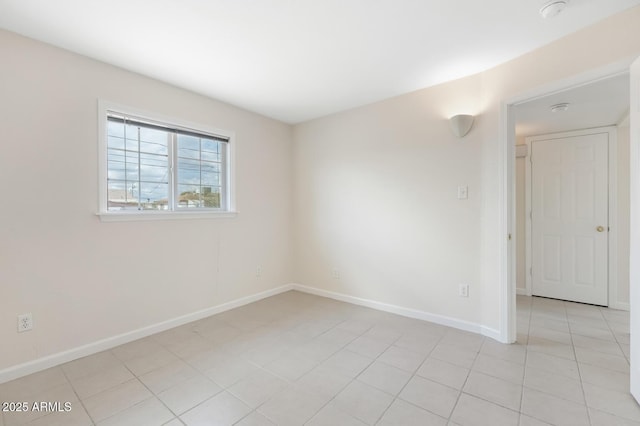 spare room featuring light tile patterned flooring and baseboards