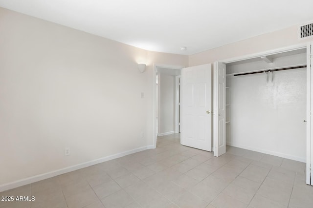 unfurnished bedroom featuring light tile patterned floors, visible vents, baseboards, and a closet