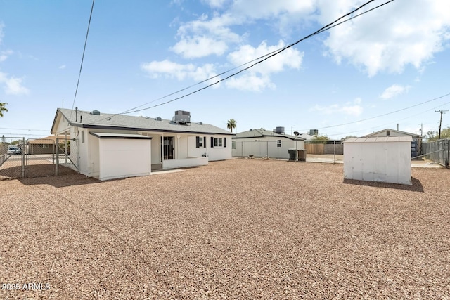 rear view of house featuring a shed, cooling unit, an outdoor structure, and a fenced backyard