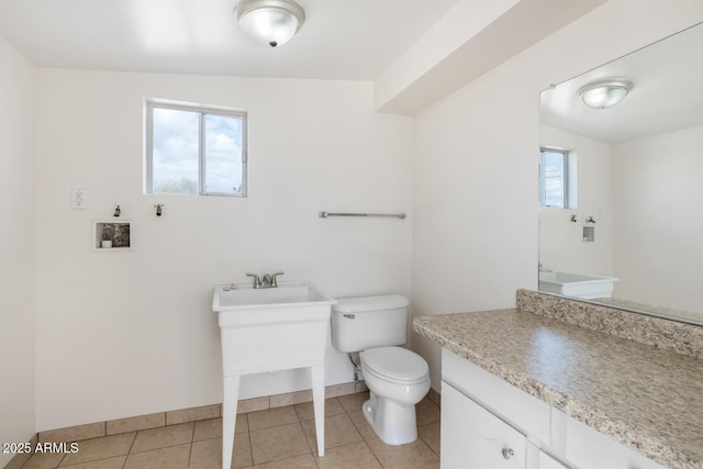 bathroom featuring tile patterned floors, toilet, a healthy amount of sunlight, and vanity