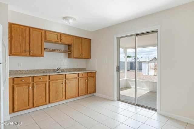 kitchen featuring a sink, baseboards, tasteful backsplash, and brown cabinetry