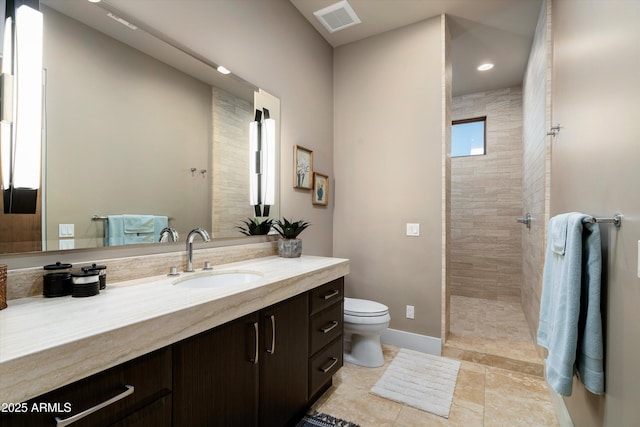 bathroom with vanity, toilet, and tiled shower