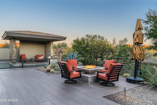 patio terrace at dusk with an outdoor fire pit and a deck