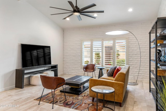 living area with lofted ceiling, recessed lighting, a ceiling fan, brick wall, and baseboards