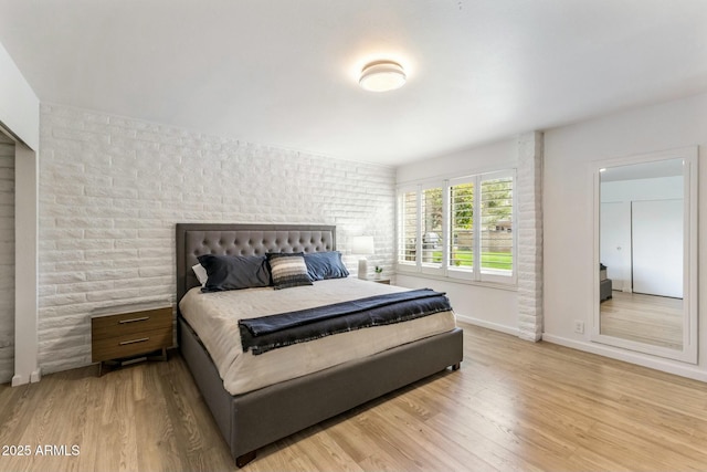 bedroom featuring baseboards, brick wall, and wood finished floors