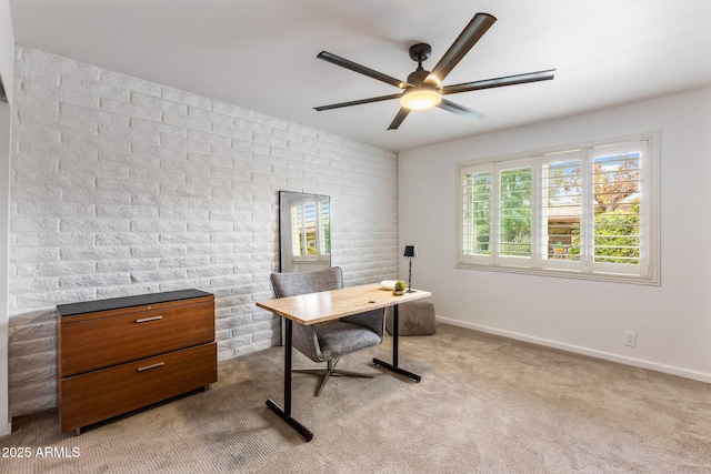 carpeted office featuring brick wall, baseboards, and a ceiling fan