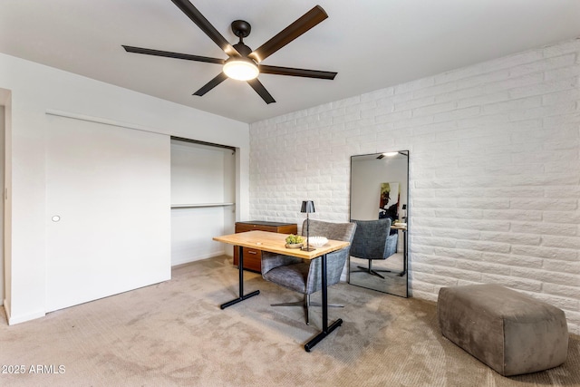 office space featuring brick wall, a ceiling fan, and light colored carpet