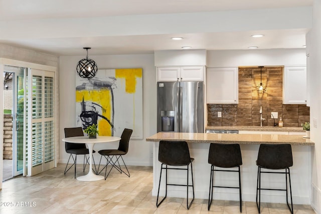 kitchen featuring appliances with stainless steel finishes, white cabinets, a sink, and a breakfast bar area