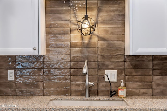 details featuring light stone countertops, tasteful backsplash, white cabinets, and a sink