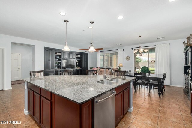 kitchen featuring ceiling fan with notable chandelier, dishwasher, pendant lighting, light stone countertops, and a kitchen island with sink