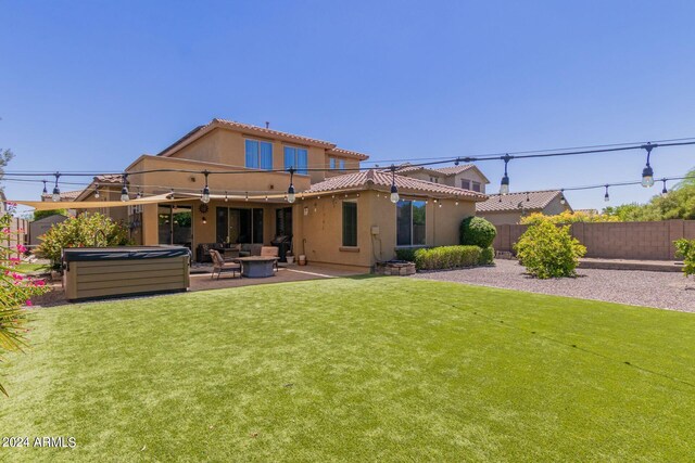 back of property with a patio, a lawn, and a hot tub