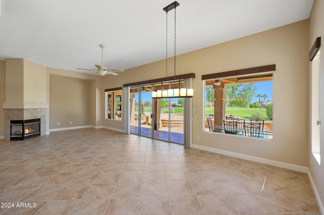 unfurnished living room featuring light tile patterned flooring, ceiling fan, a fireplace, and plenty of natural light