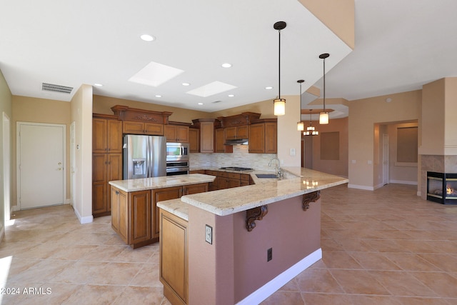 kitchen featuring a kitchen breakfast bar, kitchen peninsula, stainless steel appliances, tasteful backsplash, and a skylight