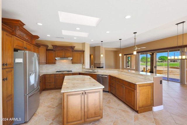 kitchen with appliances with stainless steel finishes, kitchen peninsula, a skylight, and a kitchen island