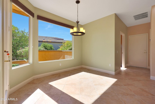 empty room with light tile patterned floors and an inviting chandelier