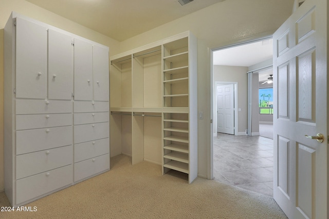 walk in closet with light colored carpet and ceiling fan