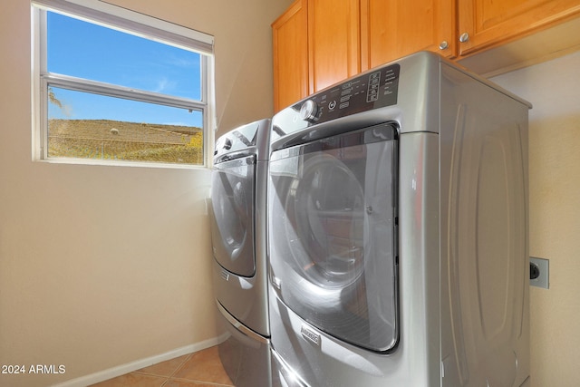 laundry area with light tile patterned flooring, washing machine and clothes dryer, and cabinets