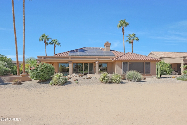 back of house featuring solar panels